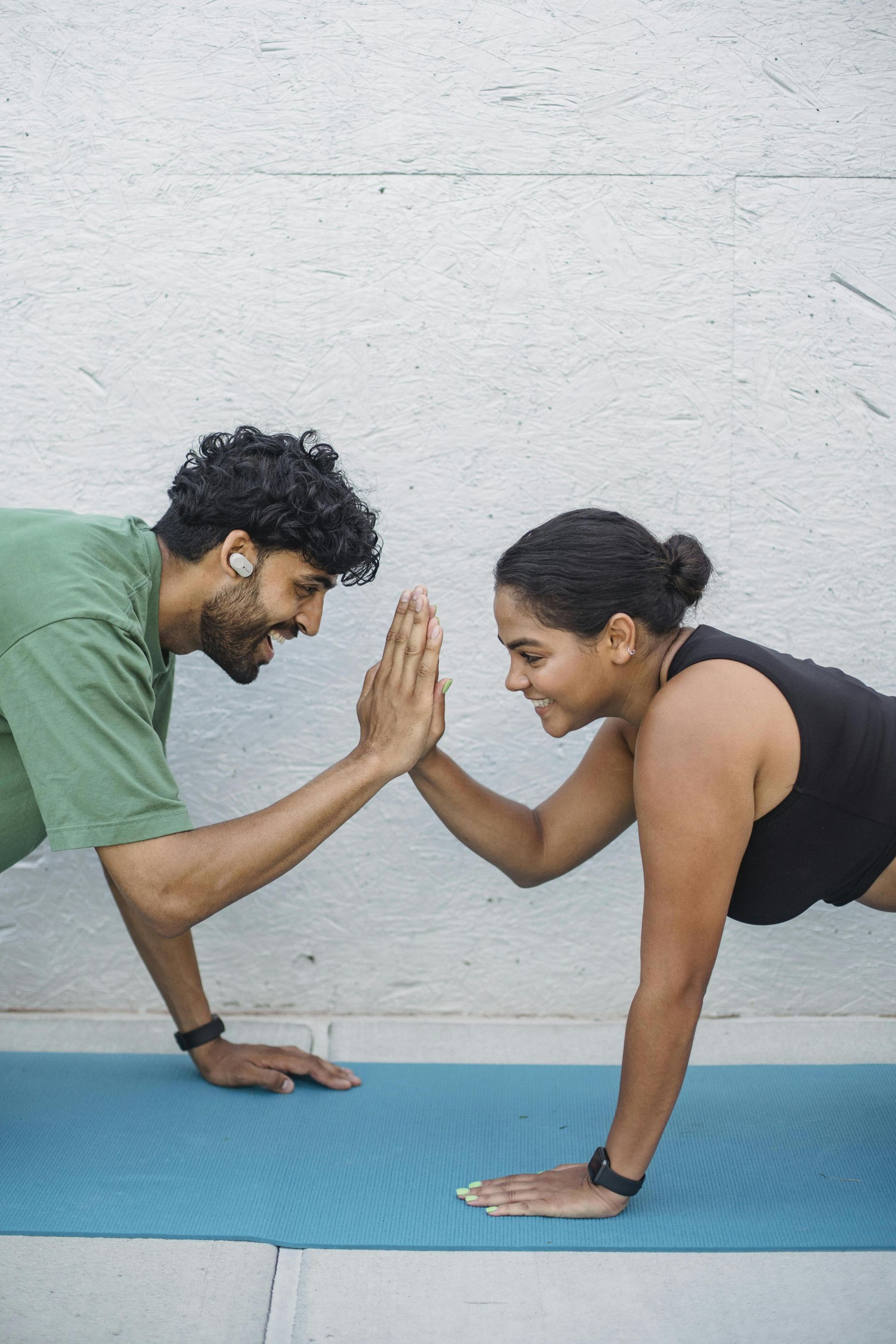 Fit couple enjoys a workout session with high fives, promoting fitness and partnership.