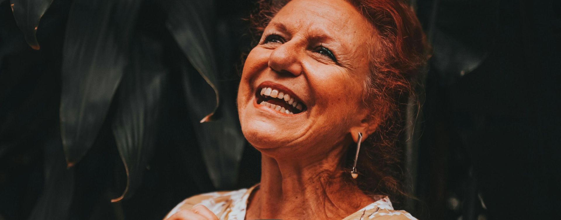 Cheerful elderly woman smiling and enjoying nature outdoors.